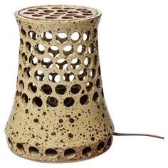 a ceramic lamp with holes in the middle and a cord attached to it, on a white background