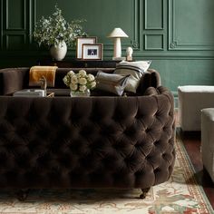 a living room with green walls and furniture in the corner, including a tufted couch