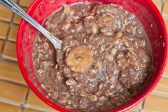 a red bowl filled with chocolate and banana oatmeal on top of a wooden table