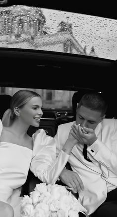 a bride and groom sitting in the back of a car