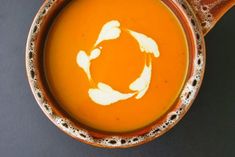 a brown bowl filled with soup on top of a black table next to a spoon