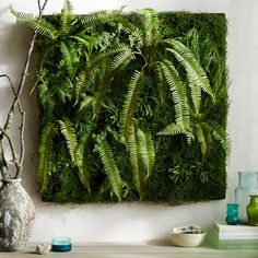 a living wall with green plants on top of it next to a potted plant