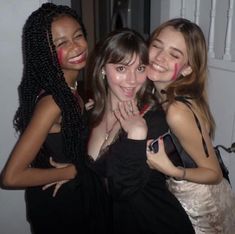 three young women posing for the camera with their arms around each other and painted on their faces