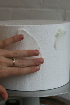 a woman's hand on top of a white cake