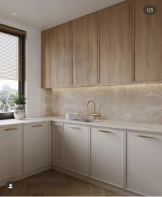 a kitchen with white cabinets and wood flooring next to a window that has blinds on the windowsill