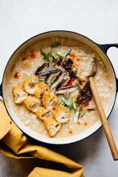 a bowl of oatmeal with mushrooms and other food items in it next to a wooden spoon