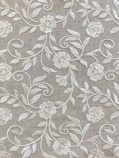 an embroidered fabric with white flowers and leaves on grey background, closeup view photo