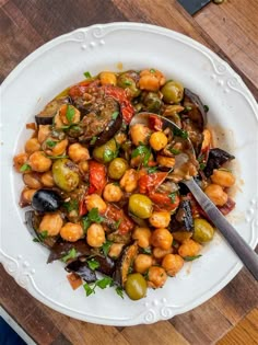 a white plate topped with beans and olives on top of a wooden cutting board