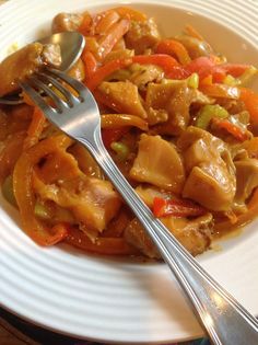 a white plate topped with meat and veggies next to a knife and fork