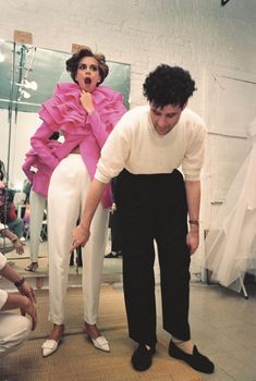 a man and woman standing next to each other in front of a mannequin