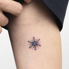 a small snowflake tattoo on the side of a woman's thigh,