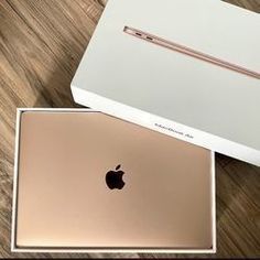 two apple laptops sitting next to each other on top of a wooden table in front of a box