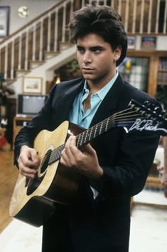 a man in a suit playing an acoustic guitar