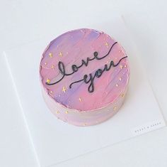 a pink cake with the words love you written on it and stars in the background