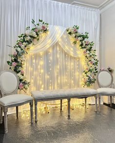 an elegant wedding setup with white chairs and flowers on the back drop cloth drapes