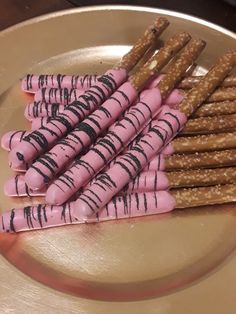 there are many pink and brown pretzels on the gold plate with chocolate drizzles