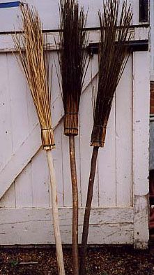 three brooms sitting on the side of a building