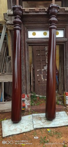 two large wooden pillars in front of an old building with peeling paint on the walls