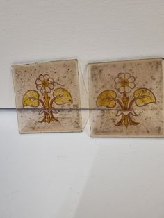 two square tiles with yellow and brown designs on them