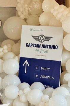 white balloons are arranged around a sign for captain antonio's 4th flight party at the airport