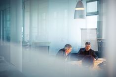 two men sitting at a table in an office