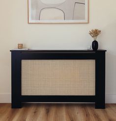 a table with a vase on top of it in front of a framed art piece