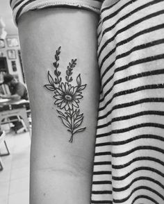 a black and white photo of a flower tattoo on the left arm with an arrow