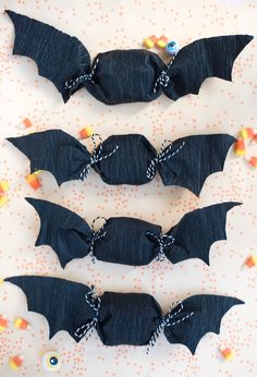 four bats made out of black paper with candy in the middle and one bat hanging from it's side