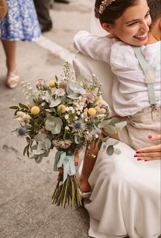 a woman sitting on the ground with a bouquet in her hand and another person standing next to her