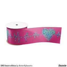 a roll of pink ribbon with blue and green hearts printed on the side, next to a roll of white paper