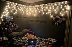 a laptop computer sitting on top of a bed in a room with lights strung from the ceiling