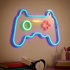 a video game controller with neon lights on the wall next to a pile of books