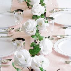 the table is set with white flowers and silverware