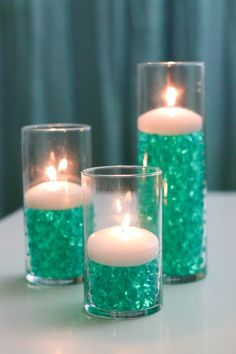 three candles with green glitter in them on a table