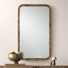 a mirror sitting on top of a wooden dresser next to a table with a lamp