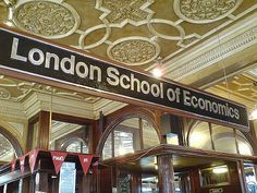 the london school of economics sign is hanging from the ceiling in an ornately decorated building