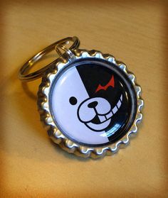 a bottle cap keychain with a cartoon bear on it's front and side