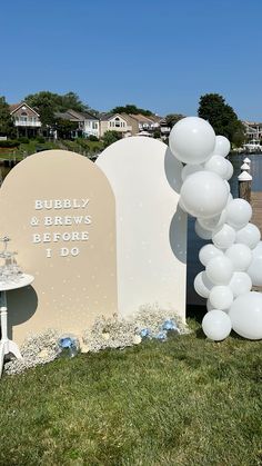 balloons and decorations are set up in front of a sign for a wedding ceremony at the water's edge