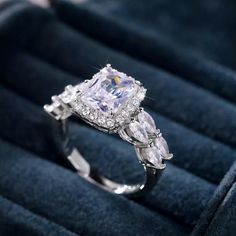 an engagement ring with two pear shaped diamonds on it in a blue velvet jewelry box