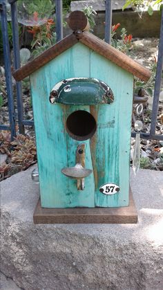 a blue birdhouse sitting on top of a cement slab