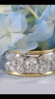 two wedding rings sitting next to each other with flowers in the background