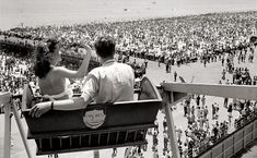 a man and woman are sitting on a ferris wheel in front of a large crowd