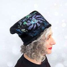 "This Nunofelted Beanie Cap in Black Merino Wool is a stylish and practical accessory that is good for any occasion. Its playful design features a cheeky tip that angles to one side, adding a touch of whimsey to your look. The hat is wet felted from high-quality Merino wool roving, making it lightweight and easy to wear.  The stained glass pattern on the beanie is inspired by the iconic floral motifs of Harry Clarke, giving it a unique and artistic appeal. Whether you are exploring the seaside or simply adding a punctuation mark to your urban street style, this Nunofelted beanie is a versatile and warm accessory that you will love to wear. And if travelling, it's packable - just fold it up and put it in your purse or rucksack. COLOUR: * This felted hat is primarily black felted wool with c Recycled Wool Sweater Hat Felted, Harry Clarke, Felted Hat, Stained Glass Pattern, Wool Roving, Wet Felt, Silk Fabrics, Glass Pattern, Beanie Cap