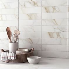 kitchen utensils in basket on counter next to white tiled wall and flooring