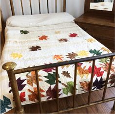 a bed with a quilt on top of it next to a dresser