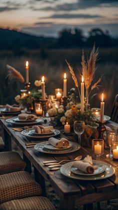 an outdoor dinner table set with candles and plates