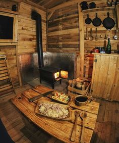 a wooden table topped with a pizza next to an open fire place in a log cabin