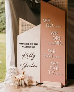 two wooden signs sitting next to each other in front of a tent with white drapes