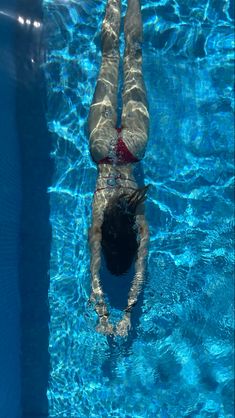 a man swimming in a pool with his feet up on the water's edge