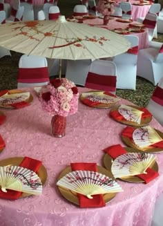 a pink table topped with lots of white and red plates covered in paper umbrellas